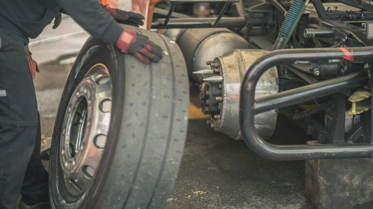 Mechanic working on replacing a tire in a professional automotive garage setting.